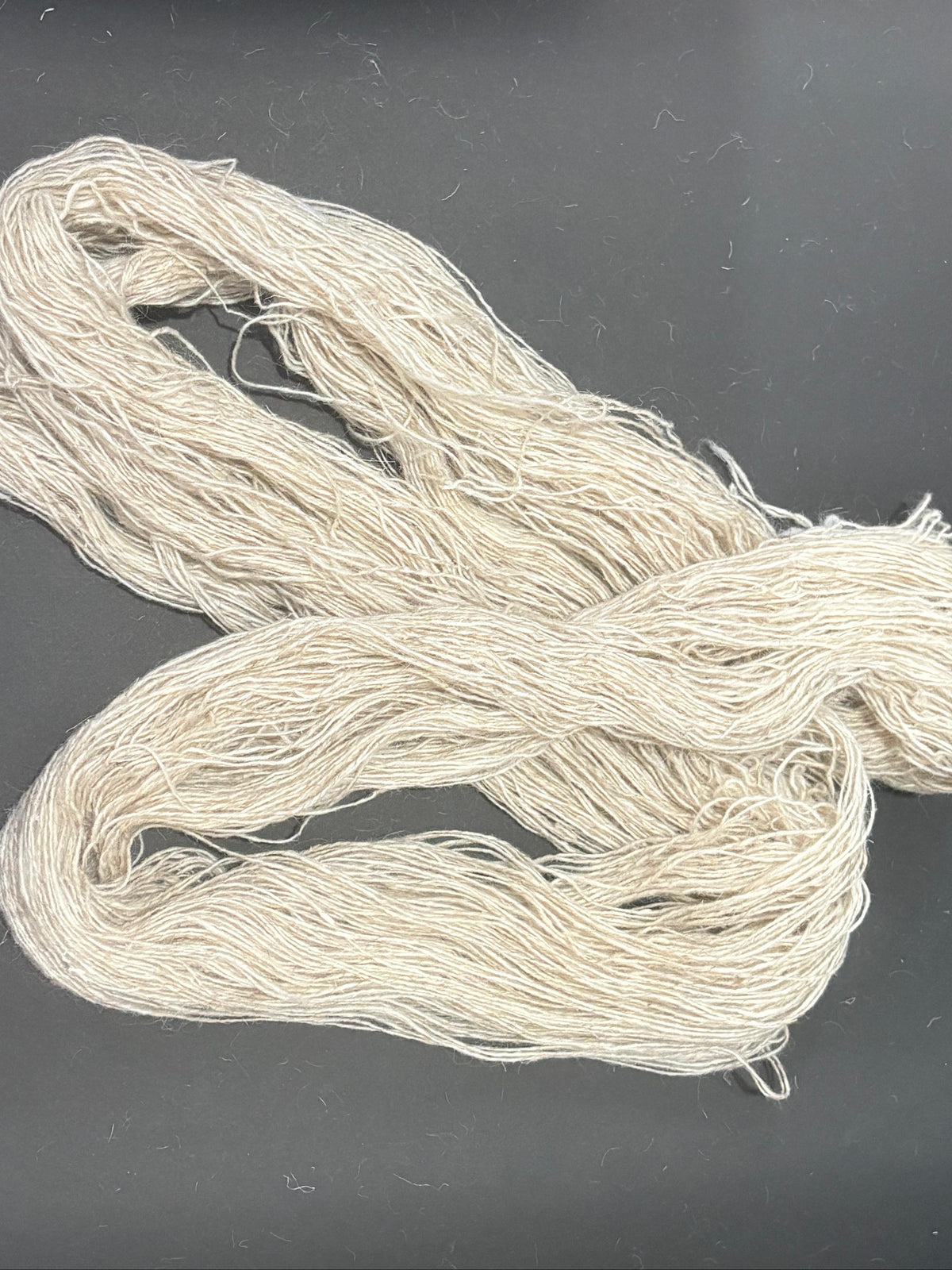 A bundle of light grey yarn coiled.